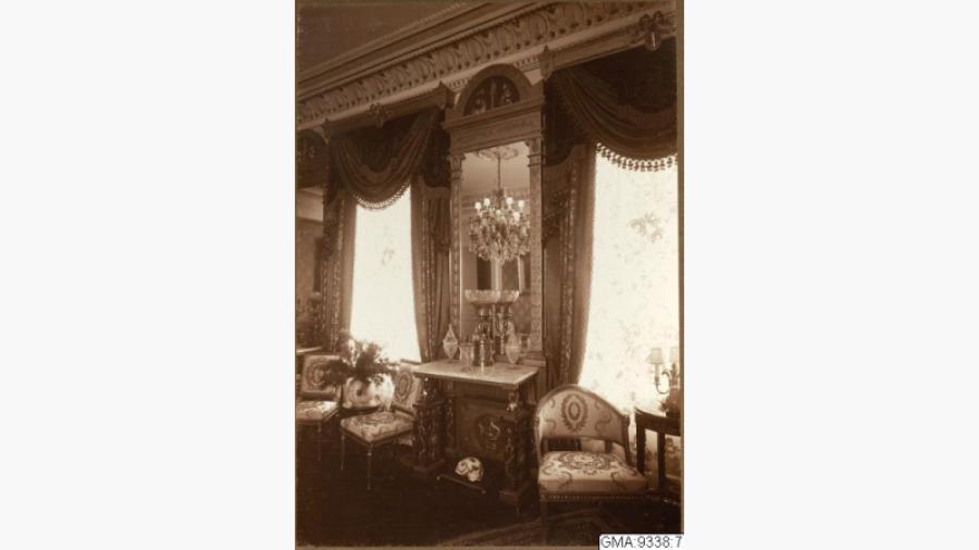 Spegel från biblioteket - Bilden 1917 ur album från Emil Haglunds hem. Spegel, konsolbord och en stol i empirestil. Spegeln troligen tillverkad av Bylander, Pehr Gustav. Källa: Databasen Carlotta, Göteborgs stadsmuseum