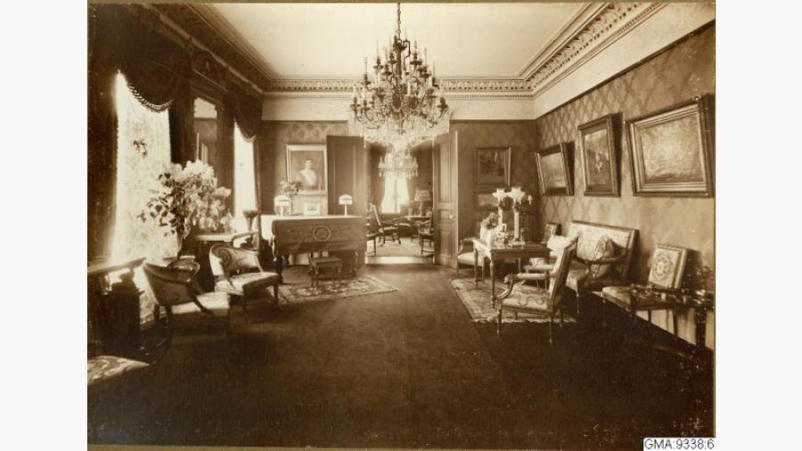 Salongen- Bild tagen 1917 ur album från Emil Haglunds hem Storgatan 41. Interiörbild med bord med 2 karmstolar, soffa och bord, blandat gustavianskt och nygustavianskt möblemang. Källa: Databasen Carlotta, Göteborgs stadsmuseum